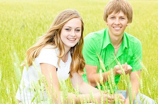 two teens sitting in a field smiling