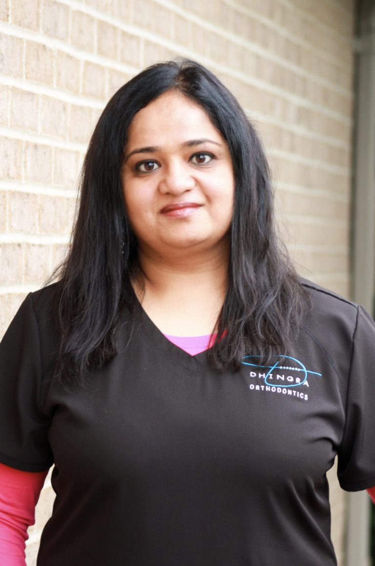 Nimisha, Dhingras scheduling coordinator, smiling while wearing pink and black srubs