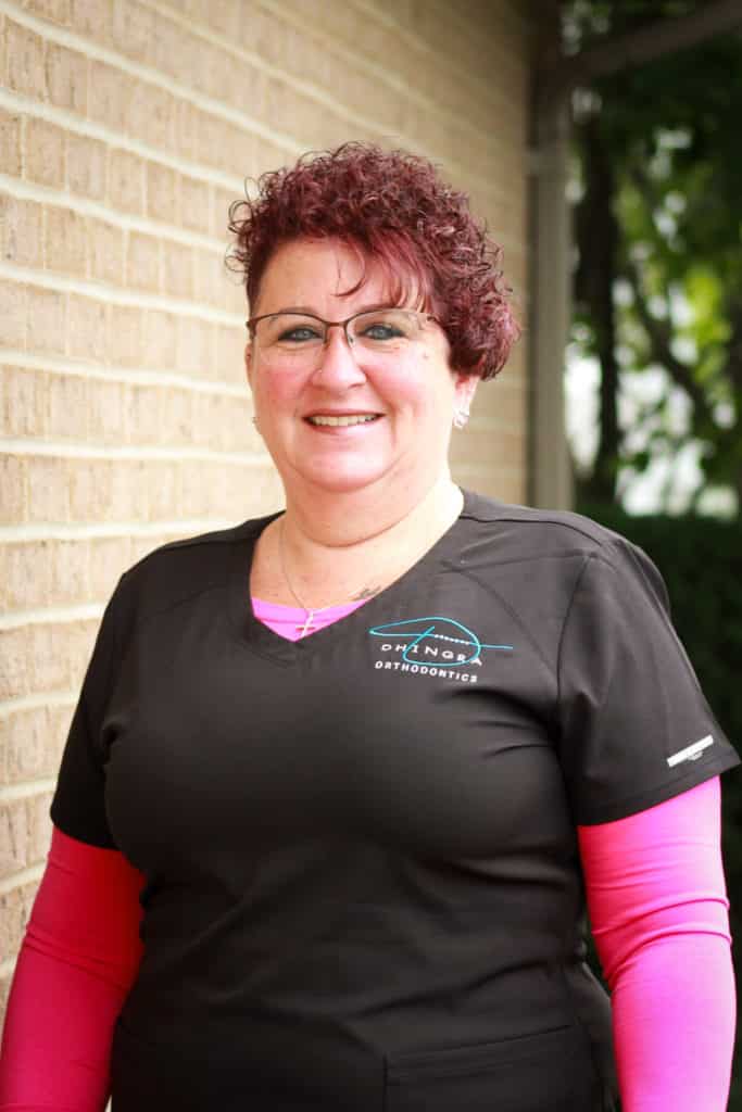 Valerie, Dhingras orthodontic assistant smiling while wearing glasses & pink and black scrubs