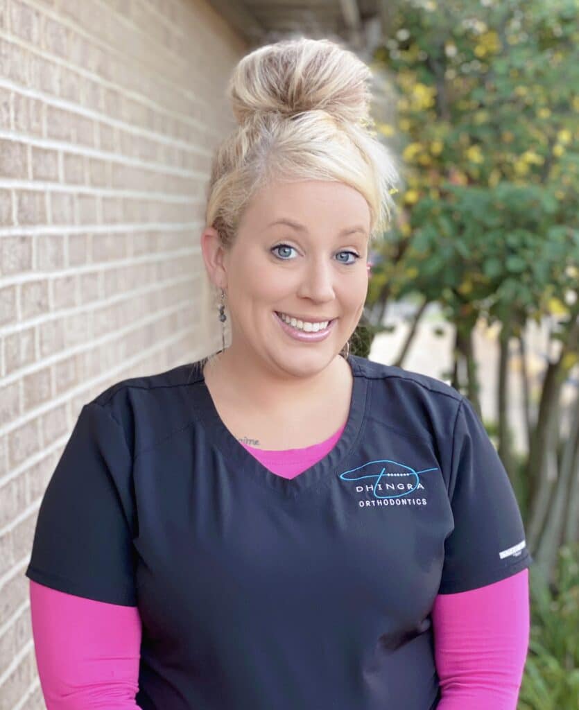 Taylor, Dhingras treatment coordinator smiling while wearing a pink and black scrubs