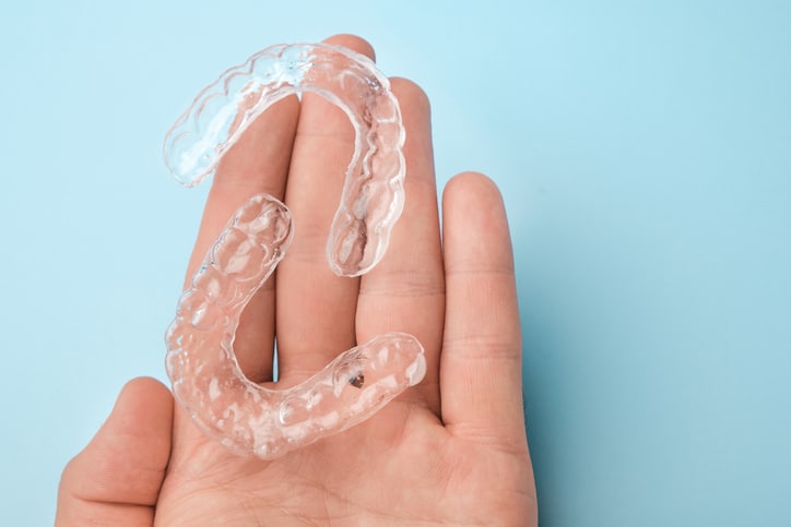 a patient holding invisalign clear braces on the palm of her hand