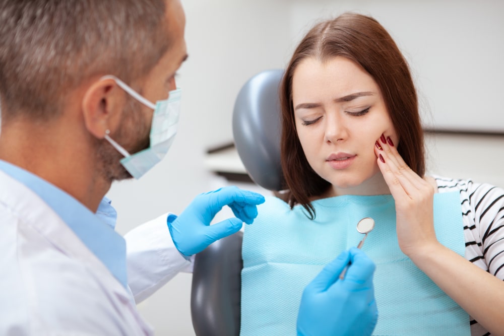 an orthodontic woman patient receiving a checkup by her orthodontist because of braces pain