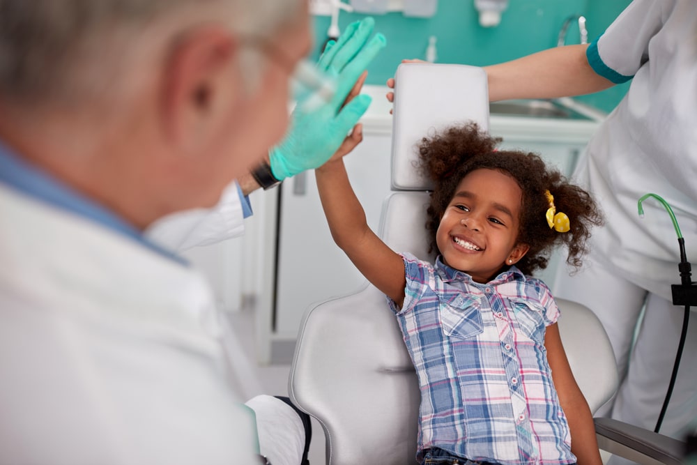 a little girl giving a high five to her orthodontist