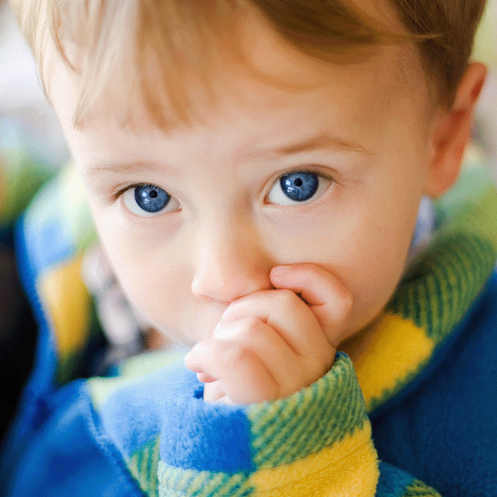 a little boy with blue eyes sucking his thumb