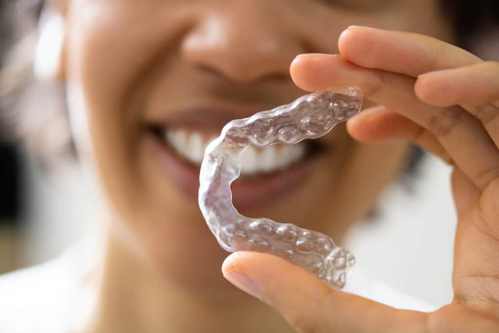 a patient holding invisalign clear aligners in front of their face