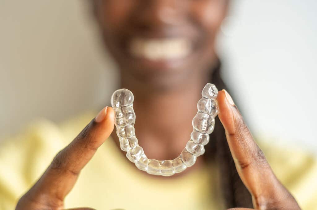 Woman with Invisalign in Beavercreek, OH holding her aligner between her index fingers