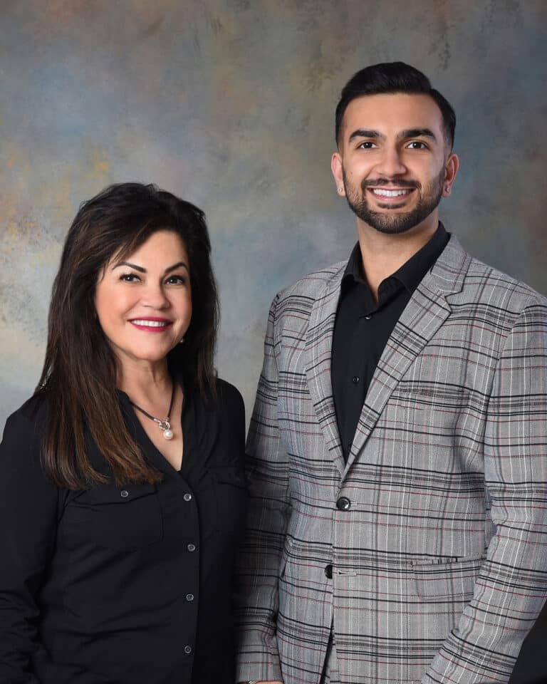 Orthodontists Drs. Seema and Azie Dhingra smiling in semi-formal attire