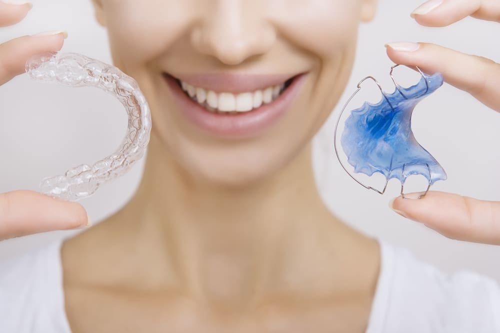 Beautiful Smiling girl Holding Retainer for Teeth (Dental Braces) and Individual Tooth Tray. Orthodontics Dental Theme, Methods of Teeth (Bite) Correction, Close-up
