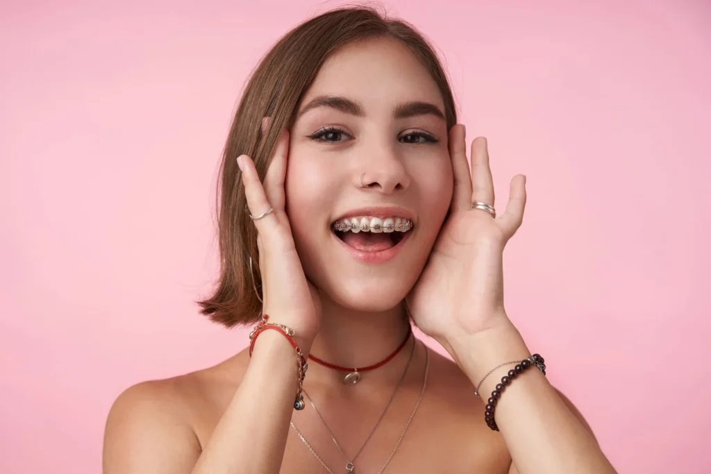 Teen with smiling with metal braces and lots of assorted jewelry around her wrists and neck