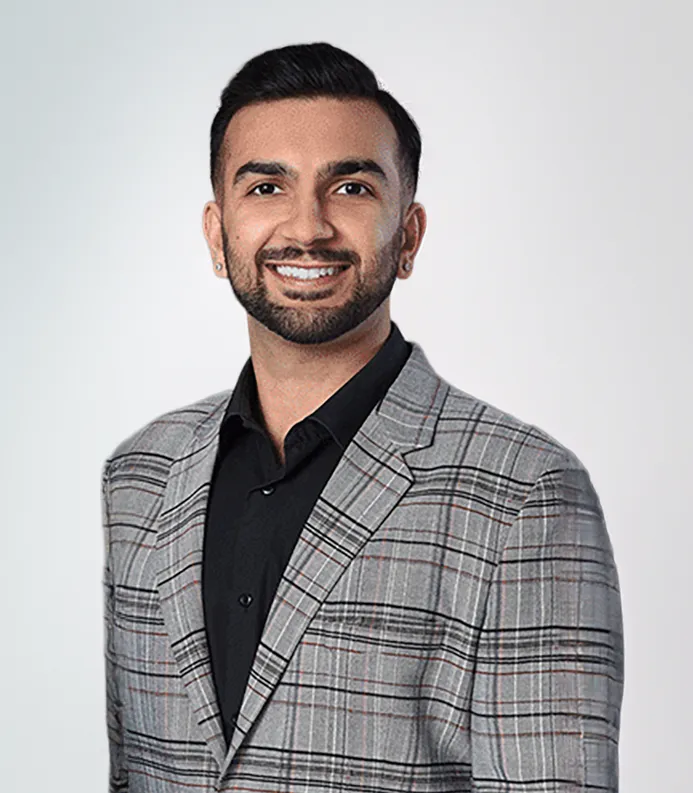Board certified orthodontist in Ohio, Dr. Azie Dhingra smiling in a gray plaid blazer and black shirt